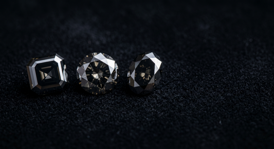Three natural loose black diamonds in round, oval and asscher cuts on dark velvet for the complete buying guide